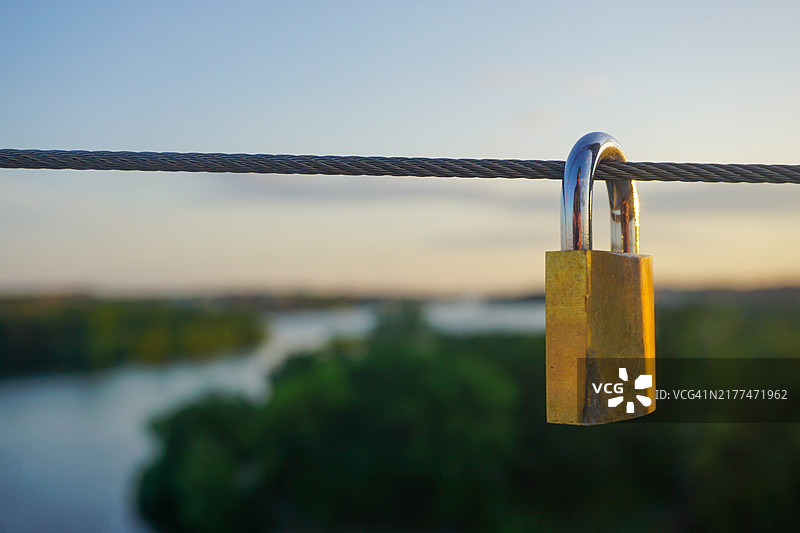桥上挂着的挂锁特写，背景是天空图片素材