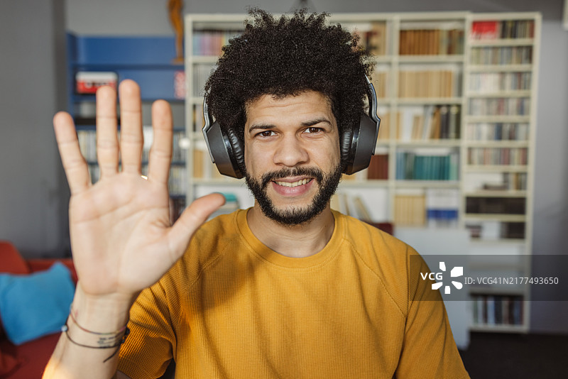 快乐的拉丁美洲男子戴着耳机通过手势进行视频通话图片素材