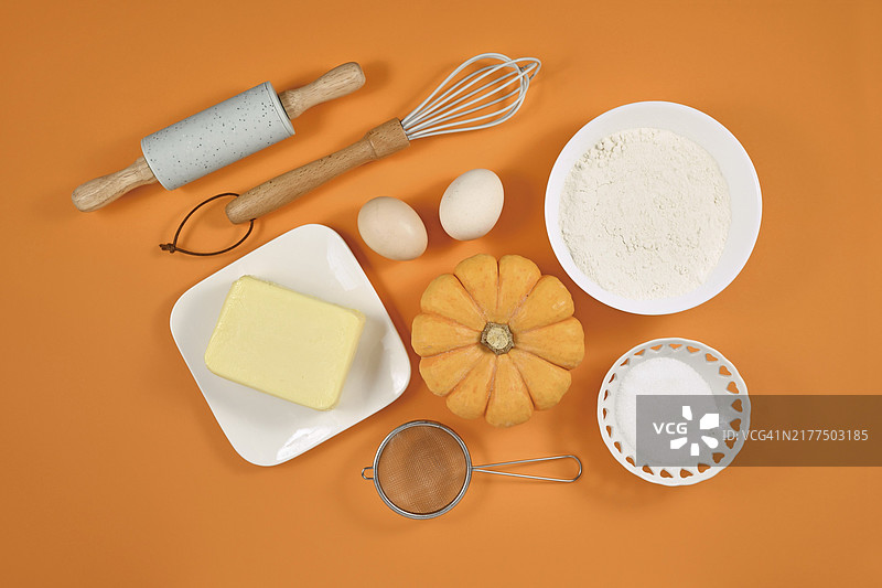 橙色背景上的南瓜派配料和烘焙工具图片素材