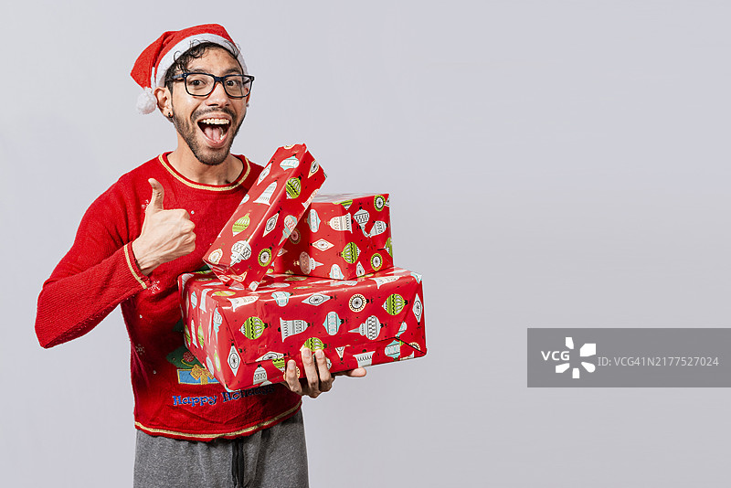 戴着圣诞帽的男人拿着圣诞礼物盒，竖起大拇指图片素材