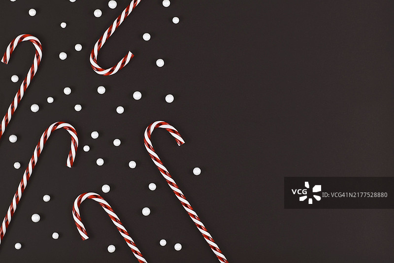 白色雪球饰品围绕的条纹圣诞糖果手杖，深色背景图片素材