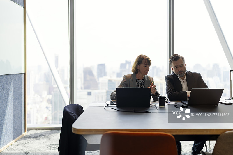 商业伙伴在会议室讨论，透过玻璃窗欣赏美丽的城市天际线图片素材