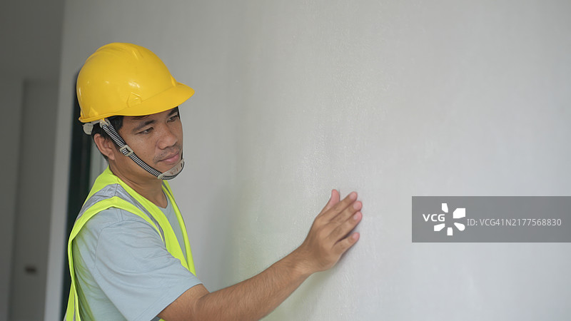 工头检查房屋墙壁的油漆颜色，建筑概念及工程原理和房屋安全性标准图片素材