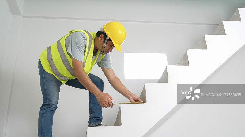 建筑工人在房子里用卷尺测量楼梯，用于瓷砖铺设和美观图片素材