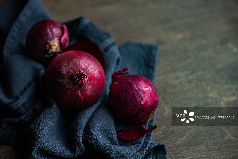 木桌餐巾上的三个红洋葱特写图片素材