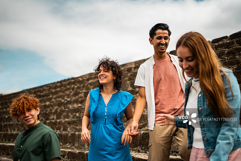 在墨西哥特奥蒂瓦坎金字塔上，游客朋友们一边交谈一边走下楼梯。图片素材