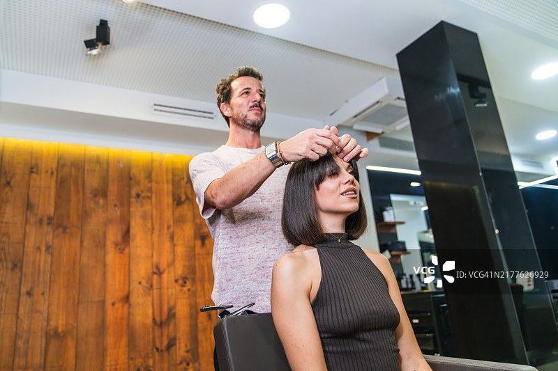 理发师在沙龙造型期间调整女子的刘海图片素材