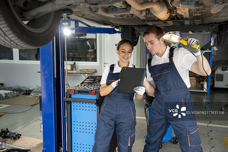 女机械师和经理在车间讨论汽车维修图片素材
