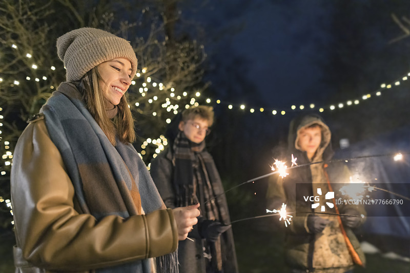 青少年在圣诞前夜在后院玩焰火棒图片素材