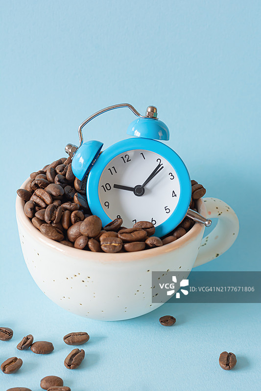 带闹钟的杯子里的咖啡豆：唤醒概念，一天活力的来源图片素材