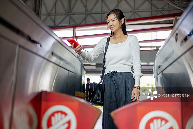 女性在火车站用手机进行非接触式支付图片素材
