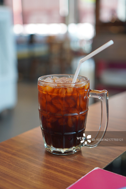 清澈的水中盛着黑冰茶，放在木桌上。饮品图片素材