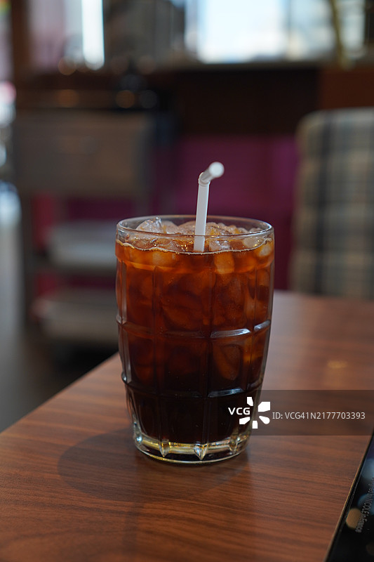 清澈的水中盛着黑冰茶，放在木桌上。图片素材