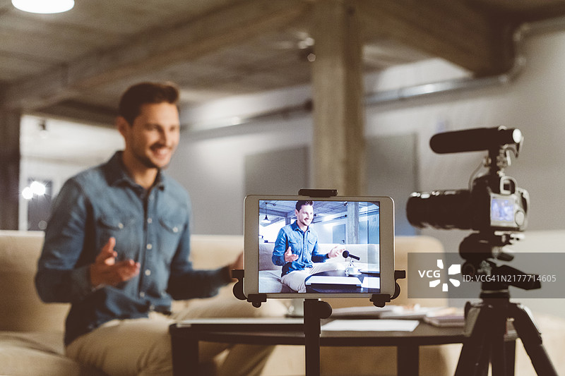 男性的视频博主正在用相机录制内容图片素材