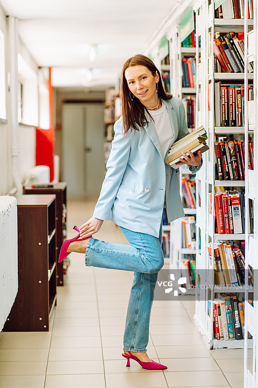 图书馆场景：现代女性整理红色高跟鞋，携带书籍用于专业和教育用途图片素材