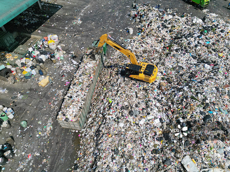 垃圾填埋场挖掘机向卡车装载废弃物图片素材