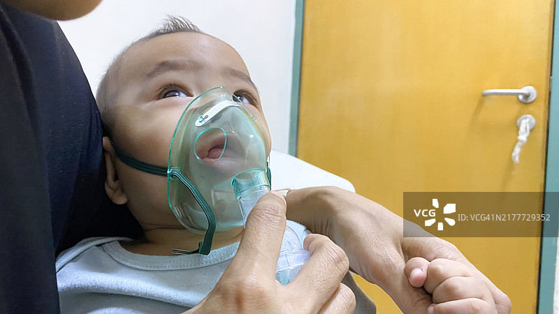 亚洲男婴在医院用雾化器吸入药物图片素材