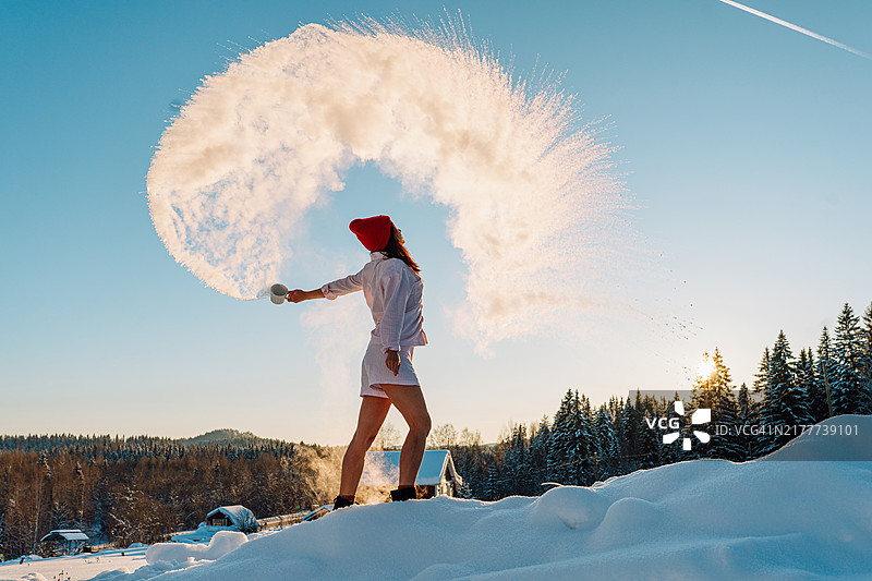 沸水遇冷空气：女子在户外倾倒热水，形成冰雾图片素材