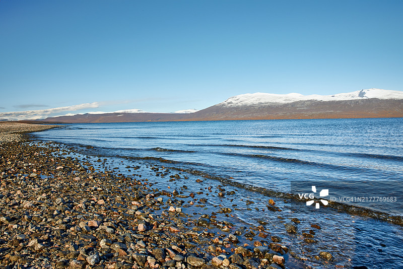 晴朗秋日里可观山景的岩石湖岸图片素材