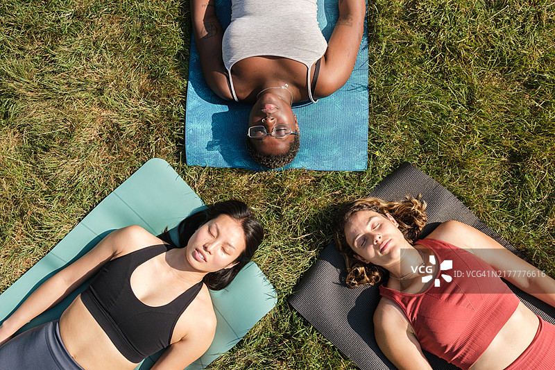 公园草地上瑜伽垫上休息的朋友顶视图图片素材