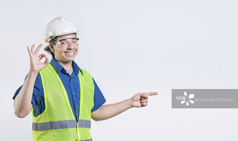 拉丁裔工程师推荐并指向一侧的肖像。 快乐的工程师指向促销隔离图片素材