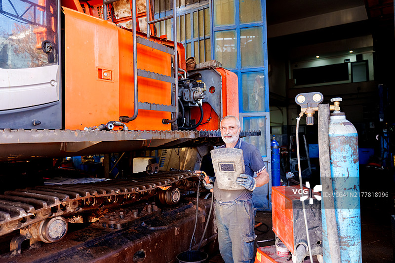 一名机械师正在大型工业机器上进行焊接工作图片素材