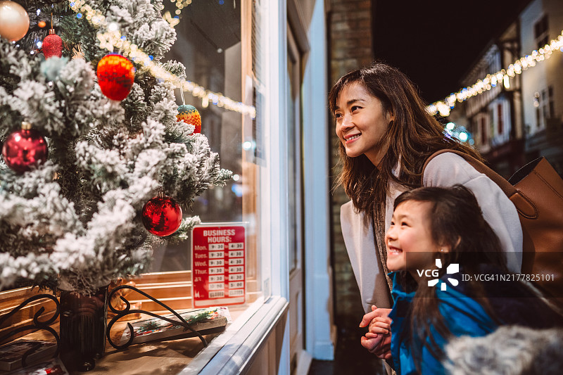 母女在节日之夜欣赏圣诞橱窗展示图片素材