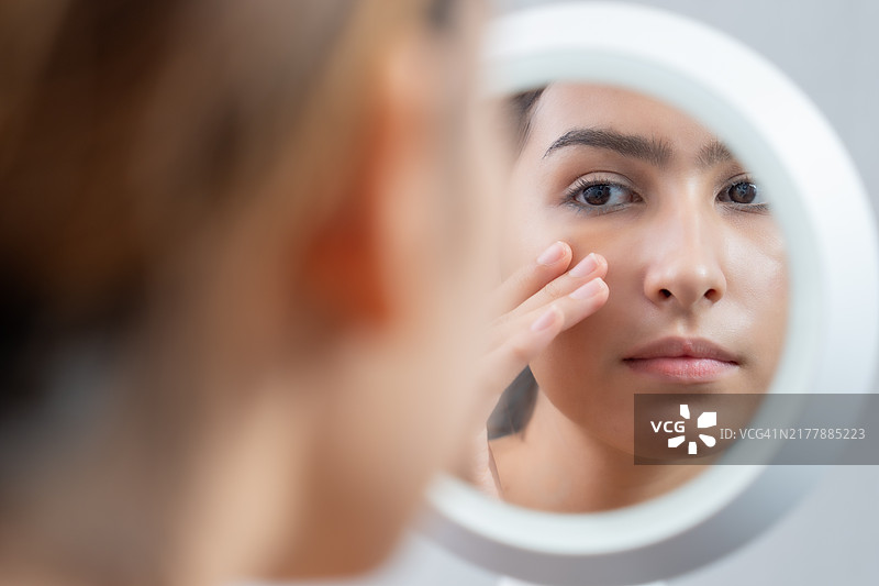 女人在镜子里检查她的皮肤图片素材