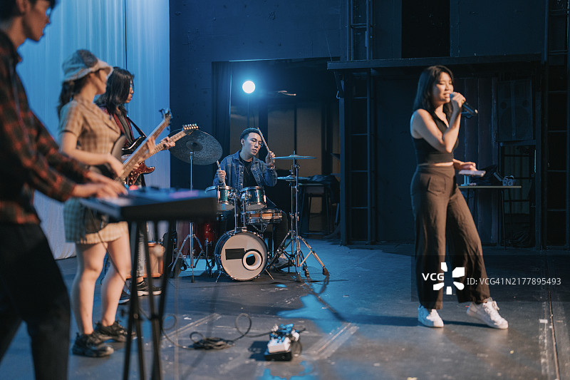 年轻的亚裔华裔主唱和现场乐队在舞台上进行多种族群体表演图片素材