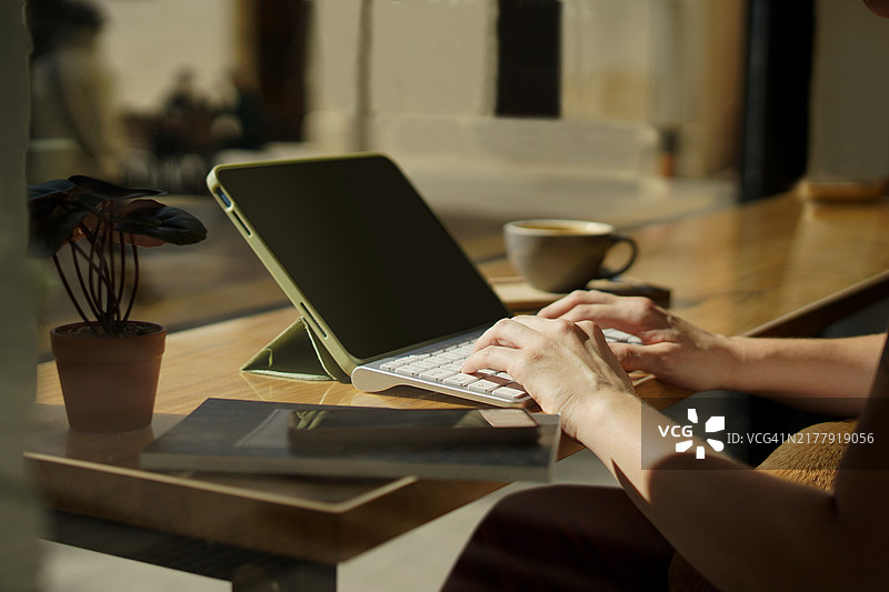 用平板电脑键盘打字并喝咖啡的手图片素材