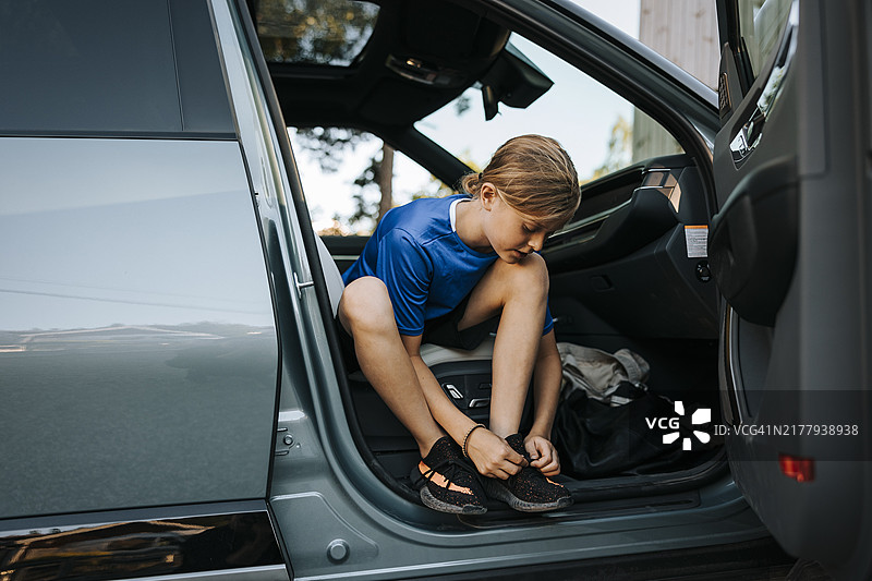 男孩坐在车里系鞋带的全身照图片素材