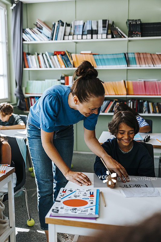 女教授在学校绘画课上帮助小学生发挥创造力图片素材