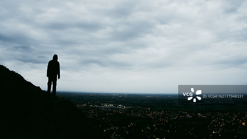 戴兜帽的神秘人物俯瞰城镇夜景图片素材