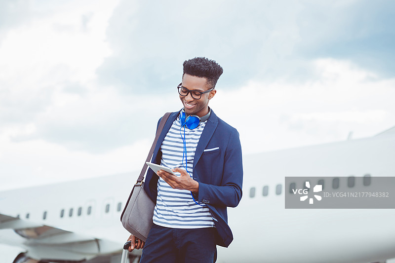 年轻商人正在飞机前使用平板电脑图片素材