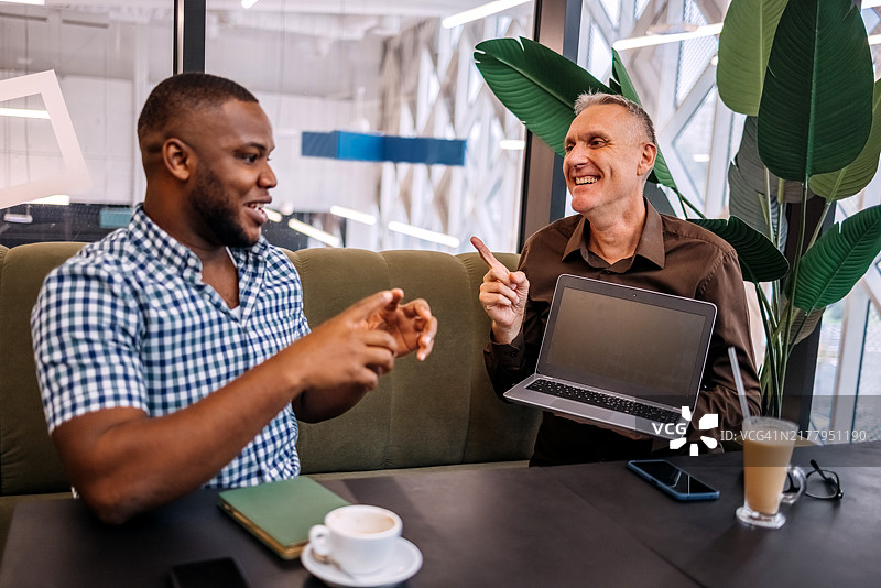 同事们在咖啡休息时一起工作，坐在笔记本电脑前图片素材
