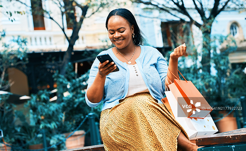 时髦女人在城市里用智能手机享受购物狂欢图片素材
