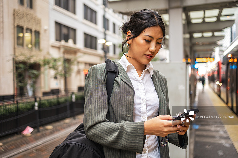 在城市火车站等候时使用智能手机的女商人图片素材