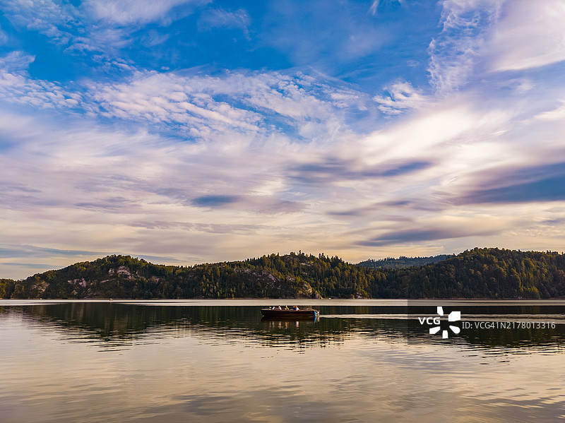 一艘船在宁静的湖面上滑行，天空景色令人叹为观止图片素材
