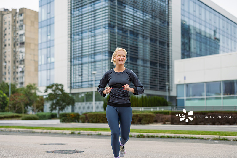 在现代玻璃建筑附近户外跑步的女人图片素材