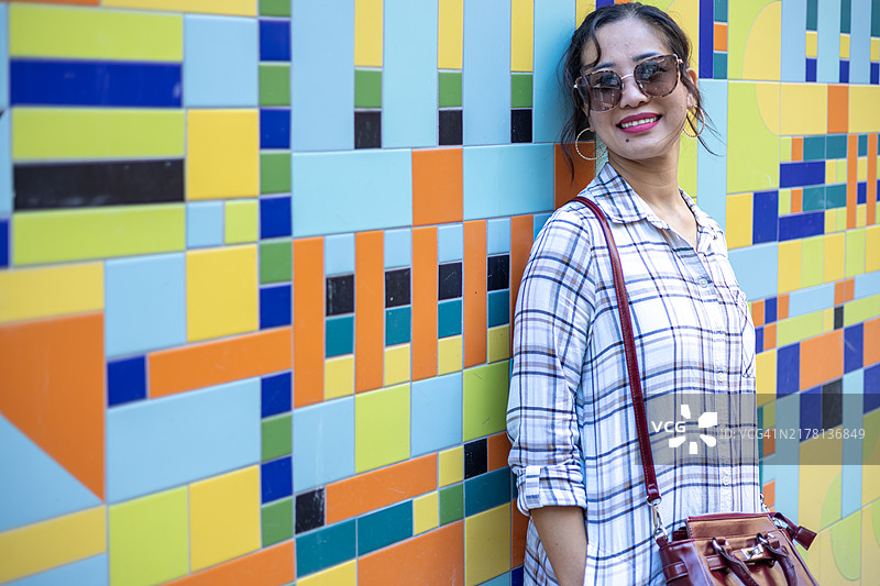 年轻的菲律宾女性站在英国布里斯托尔色彩斑斓的瓷砖背景前图片素材