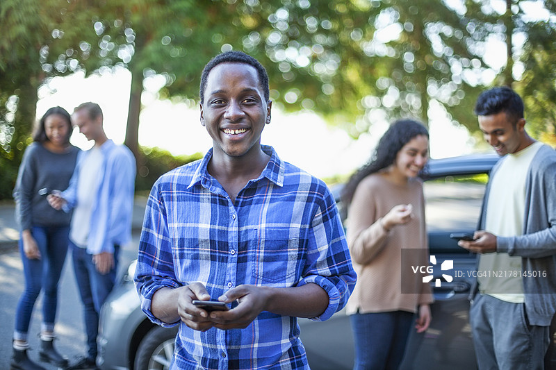 年轻黑人男孩在停车场与朋友们用手机图片素材