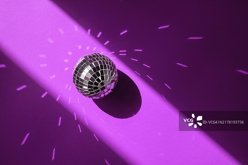 节日背景：阳光下紫色背景的银色迪斯科球，圣诞/生日派对主题图片素材