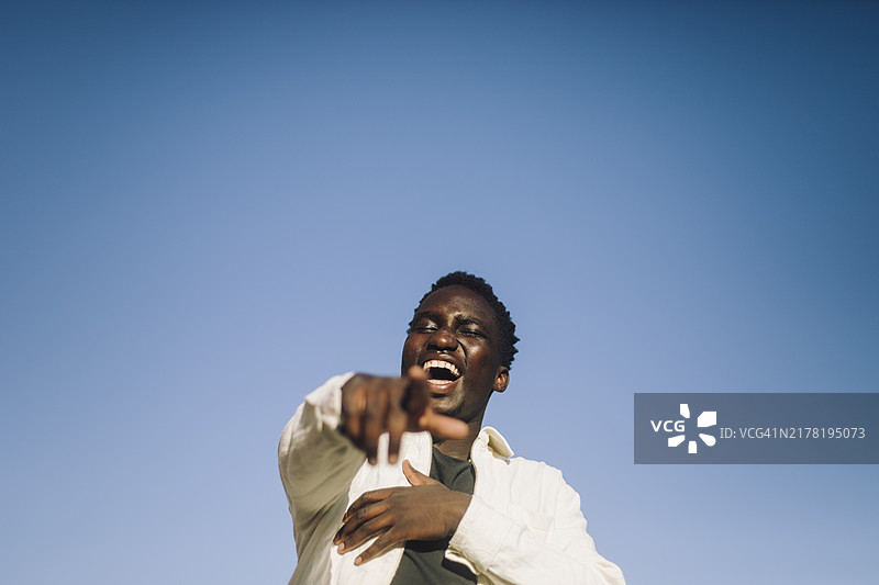 仰视蓝天下享受的年轻男子肖像图片素材
