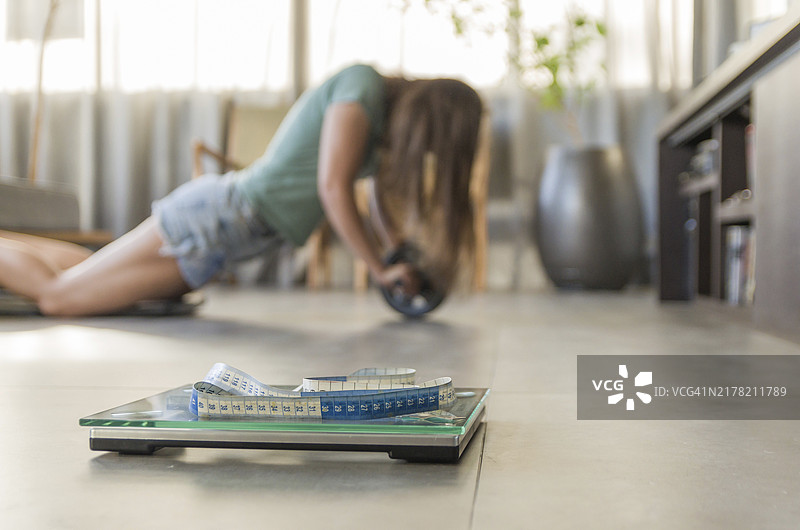 减肥失败的概念：前景是体重秤，背景是沮丧的女人图片素材