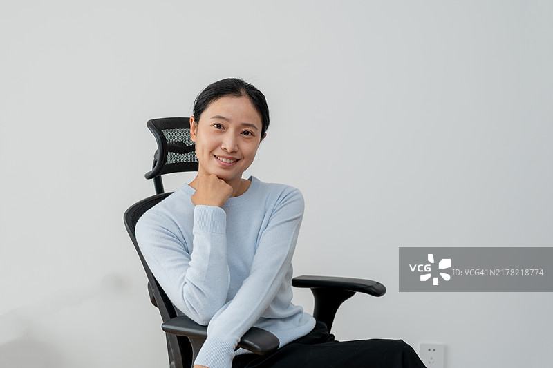 一位穿着白衬衫的亚洲女性坐在椅子上图片素材