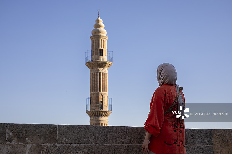 站在马尔丁一座清真寺宣礼塔前的年轻穆斯林女性图片素材