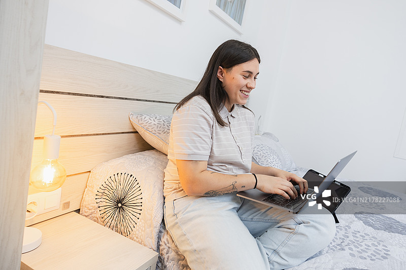 年轻女人在舒适现代的卧室里用笔记本电脑工作图片素材