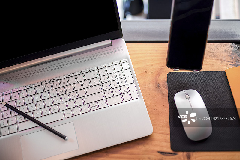 整洁办公桌上的笔记本电脑、鼠标与智能手机图片素材