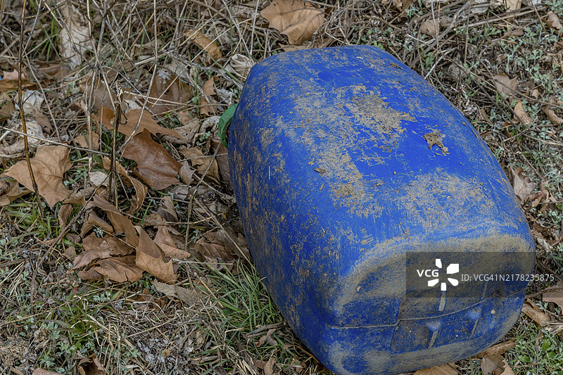 在韩国，褪色的蓝色桶被遗弃在落叶中图片素材