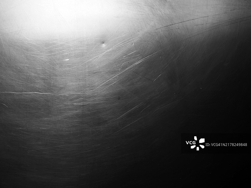 在阳光与阴影之间，巴黎的一面光亮铝墙特写，表面有划痕。黑白色调。图片素材